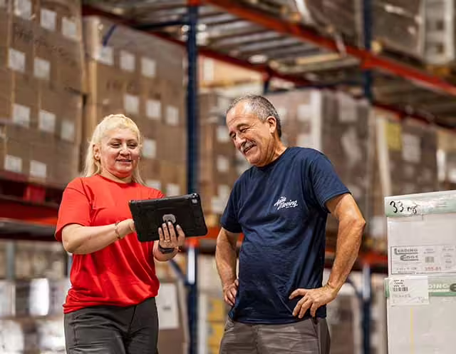 Commercial moving professionals handling wrapped items in a storage space